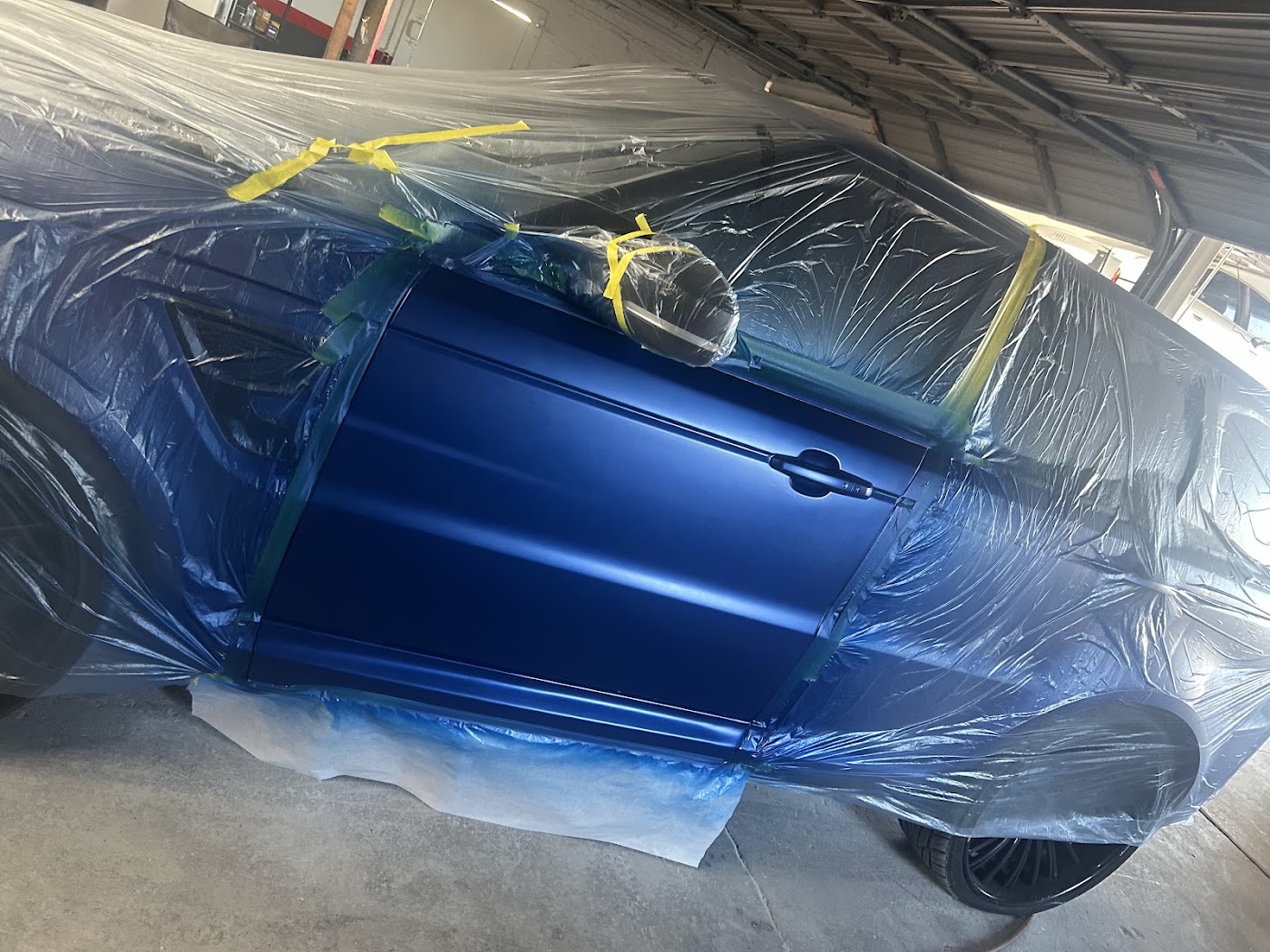 Factory-matched blue paint on a car door in the paint booth at our Phoenix auto body shop on 24th St